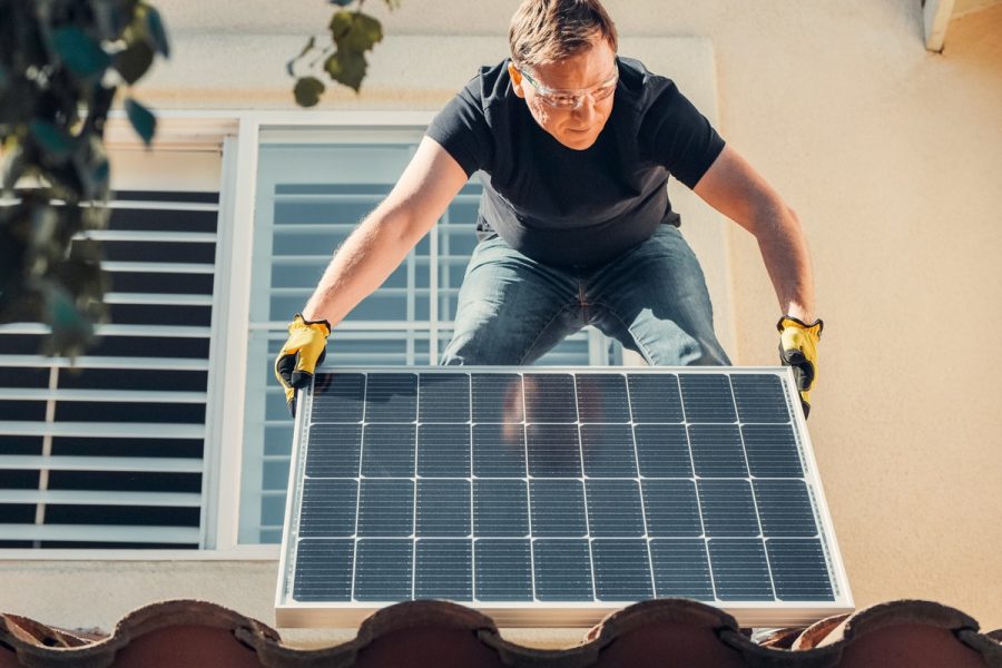 installateur posant un panneau solaire sur le toit d'une maison