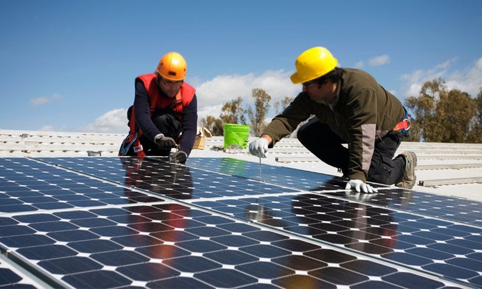 Ouvriers en train d'installer et nettoyer des panneaux solaires photovoltaïques sur une toiture