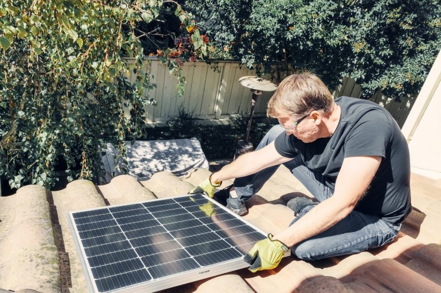 ouvrier qui pose panneau solaire sur toiture de maison